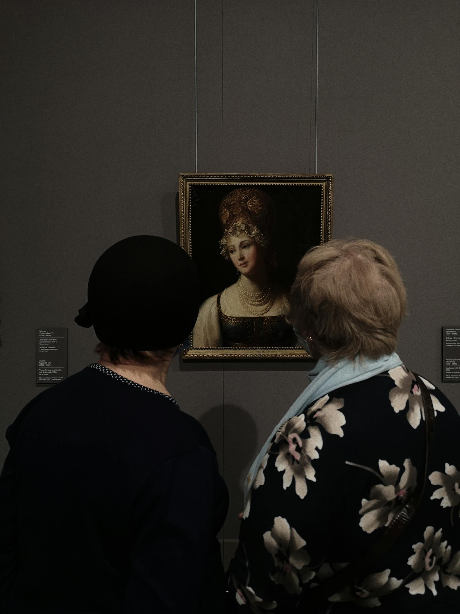 Two women admire a classic portrait in a museum, creating a timeless and introspective scene.